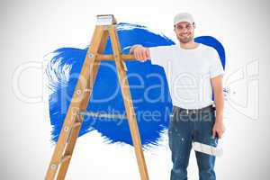 Composite image of happy man with paint roller standing by ladde