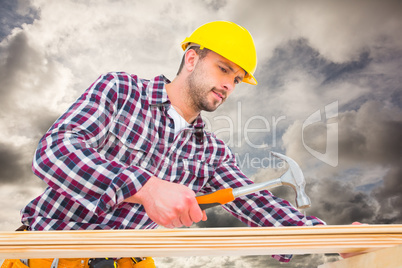 Composite image of handyman using hammer on wood