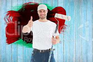 Composite image of happy man with paint roller gesturing thumbs up