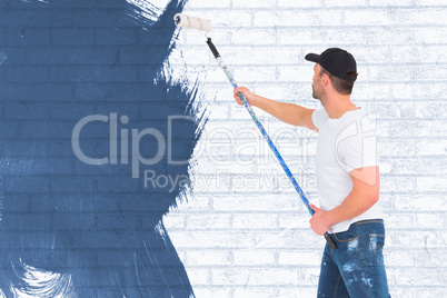 Composite image of handyman painting with roller