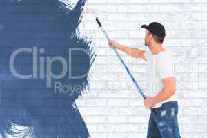 Composite image of handyman painting with roller