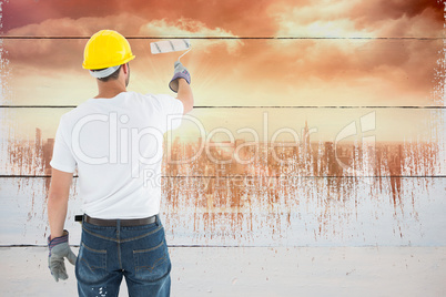 Composite image of man wearing hardhat while using paint roller