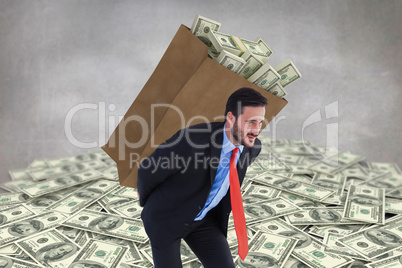 Composite image of businessman carrying bag of dollars