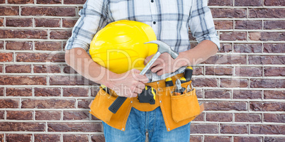 Composite image of technician holding hammer and hard hat