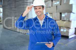 Composite image of happy supervisor wearing hard hat while holdi