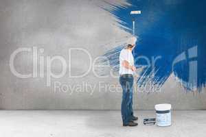 Composite image of man using paint roller on white background