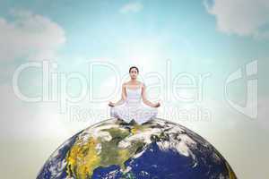 Composite image of peaceful woman in white sitting in lotus pose