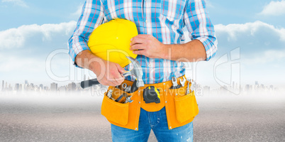 Composite image of manual worker wearing tool belt while holding