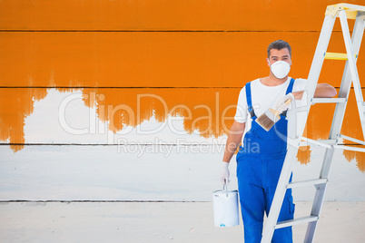 Composite image of handyman with paintbrush and can leaning on l