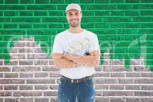 Composite image of happy man with paint roller standing arms cro