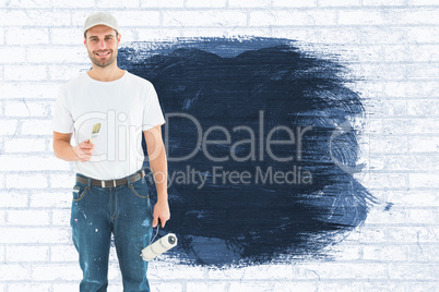 Composite image of happy man holding paint roller and paintbrush