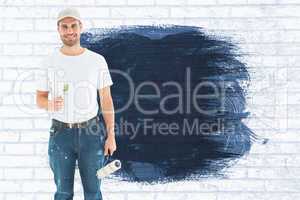 Composite image of happy man holding paint roller and paintbrush