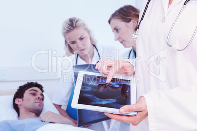 Composite image of doctor looking at xray on tablet