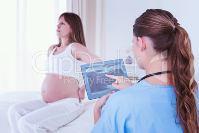 Composite image of doctor looking at xray on tablet