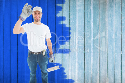 Composite image of happy man wearing gloves while holding paint