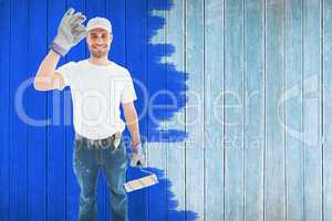 Composite image of happy man wearing gloves while holding paint