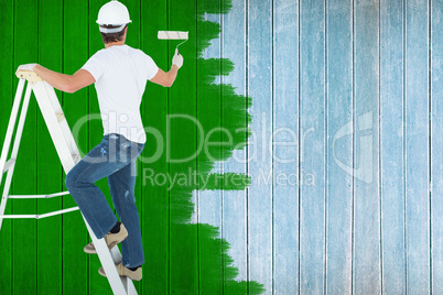 Composite image of man on ladder painting with roller