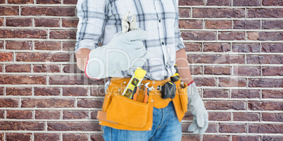 Composite image of technician with tool belt around waist holdin