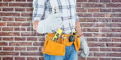 Composite image of technician with tool belt around waist holdin