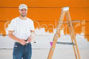 Composite image of man holding paint roller while standing by la