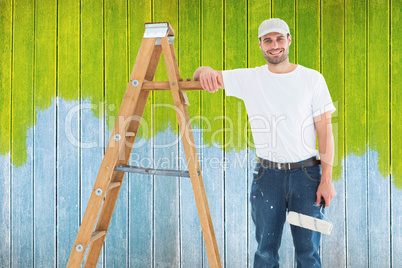 Composite image of happy man with paint roller standing by ladde