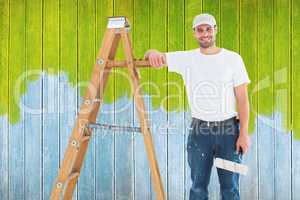 Composite image of happy man with paint roller standing by ladde