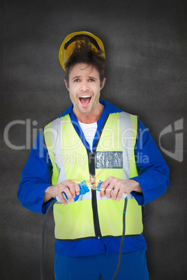 Composite image of electrician getting a shock while holding wir