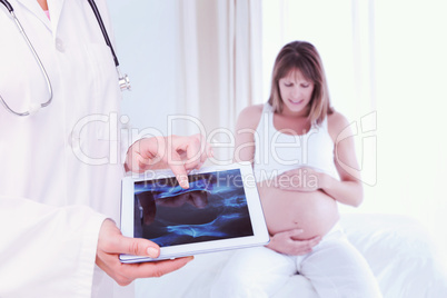 Composite image of doctor looking at xray on tablet