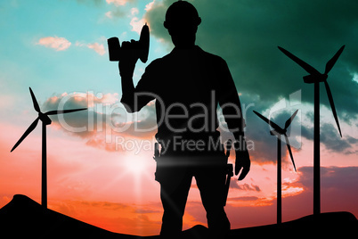 Composite image of confident male repairman holding drill machin
