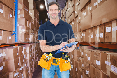 Composite image of handsome carpenter writing on clipboard