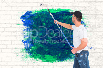 Composite image of handyman painting with roller