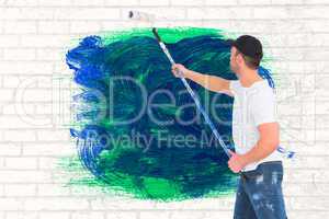 Composite image of handyman painting with roller