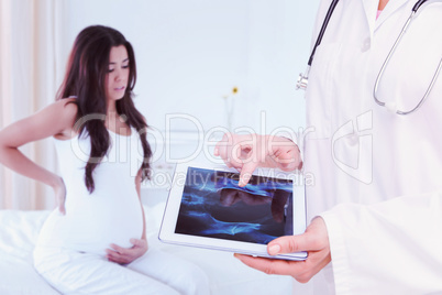 Composite image of doctor looking at xray on tablet