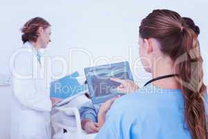 Composite image of doctor looking at xray on tablet