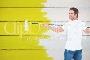 Composite image of happy man using paint roller
