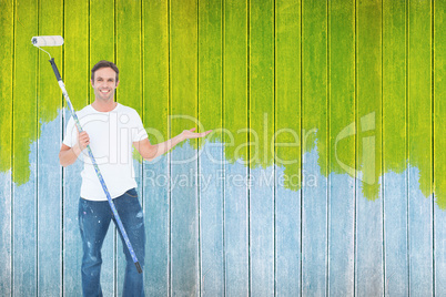 Composite image of man gesturing while holding paint roller