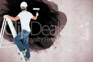 Composite image of man on ladder painting with roller