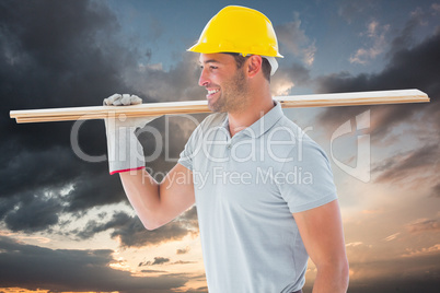 Composite image of worker with plank of wood