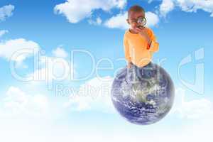 Composite image of cute boy looking through a magnifying glass