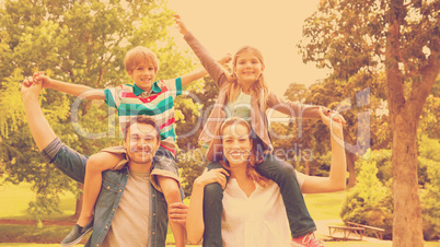 Parents carrying kids on shoulders at park