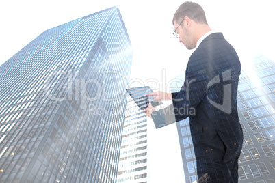 Composite image of businessman using his tablet pc