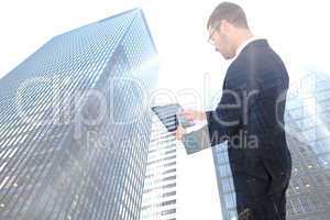 Composite image of businessman using his tablet pc