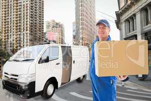 Composite image of happy delivery man showing cardboard box