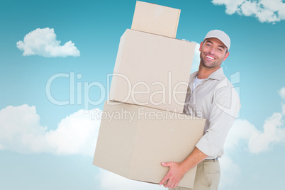 Composite image of delivery man carrying cardboard boxes