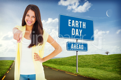 Composite image of happy casual woman pointing to camera