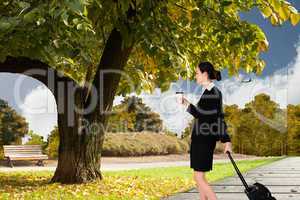 Composite image of businesswoman pulling her suitcase holding co