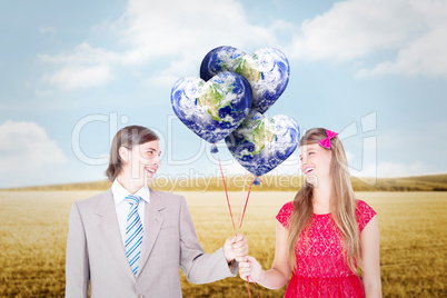 Composite image of smiling geeky couple holding red balloons