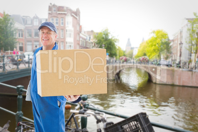 Composite image of happy delivery man showing cardboard box