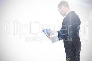 Composite image of businessman using his tablet pc