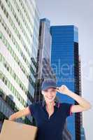 Composite image of happy delivery woman holding cardboard box